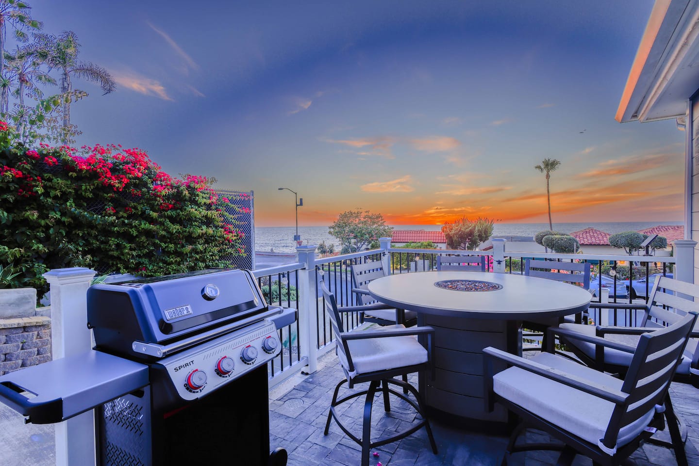Ocean-view deck with a BBQ and dining table glowing at sunset
