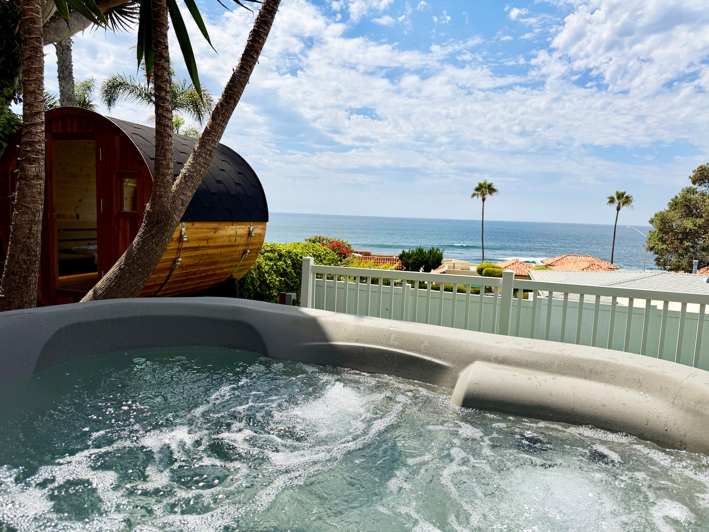 Ocean-view hot tub and spa bubbling beside the barrel sauna at Nalu House